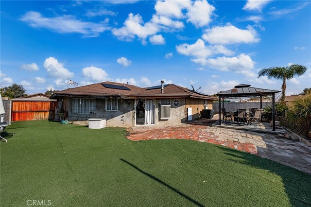 rear view of house featuring a yard, a gazebo, a patio area, and solar panels