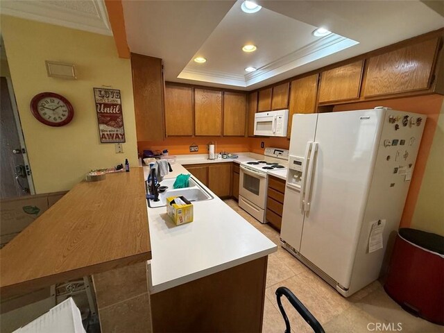 kitchen featuring sink, crown molding, a tray ceiling, kitchen peninsula, and white appliances