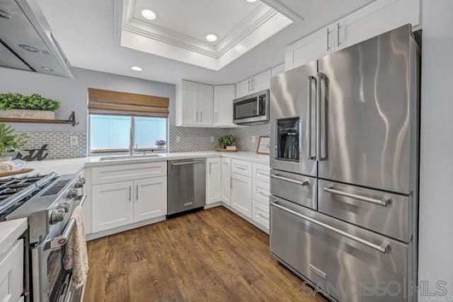 kitchen with high end appliances, white cabinets, and decorative backsplash