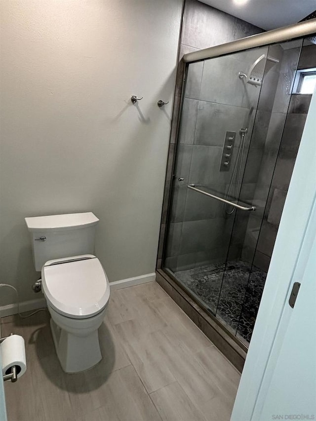 bathroom featuring a shower with door and toilet