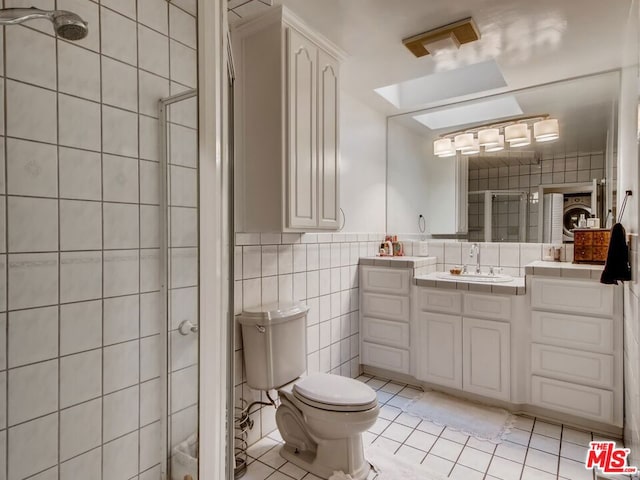 bathroom featuring tile walls, tile patterned flooring, vanity, walk in shower, and toilet