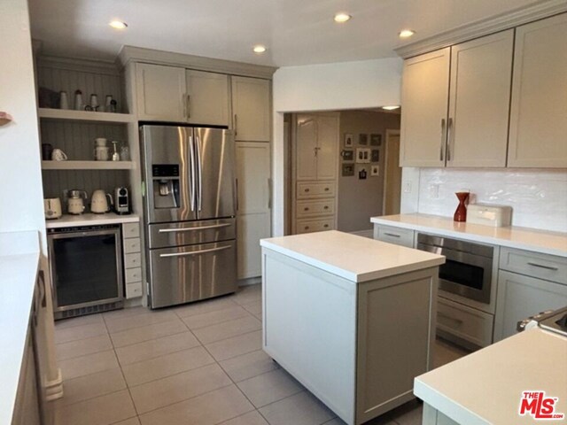 kitchen featuring stainless steel refrigerator with ice dispenser, a kitchen island, and gray cabinetry