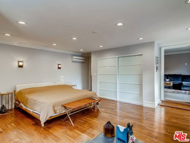 bedroom featuring hardwood / wood-style flooring and a wall unit AC