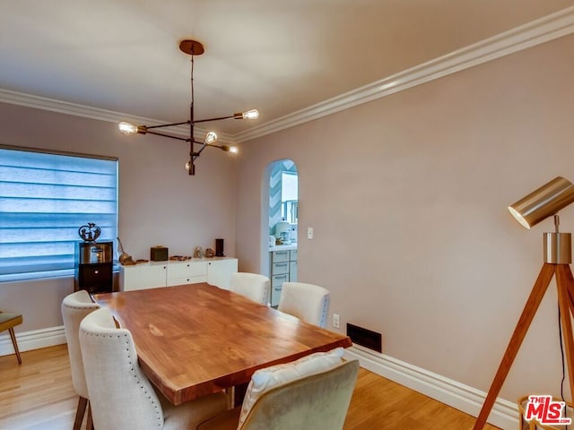 dining area with crown molding, a notable chandelier, light hardwood / wood-style flooring, and a wealth of natural light