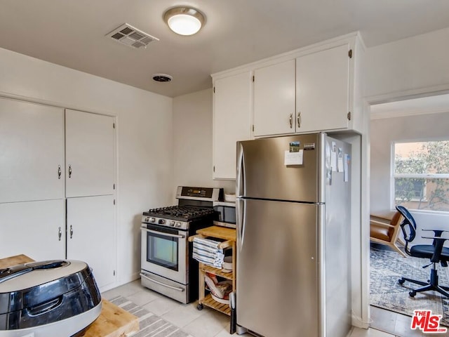 kitchen with stainless steel appliances, light tile patterned flooring, and white cabinets