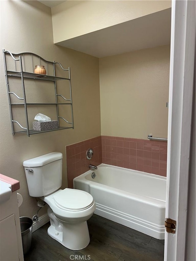 bathroom featuring wood-type flooring, a tub to relax in, vanity, and toilet