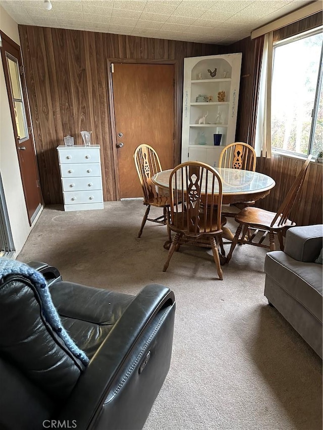 carpeted dining area with wood walls