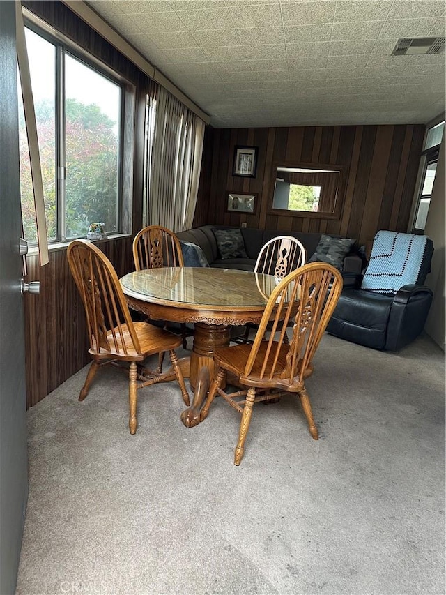 dining area with carpet floors and wood walls