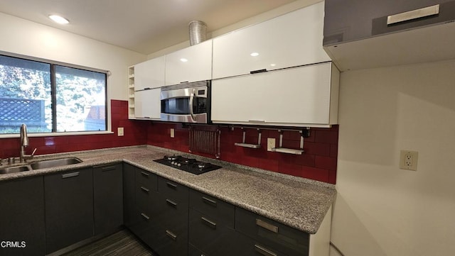 kitchen featuring backsplash, black gas stovetop, sink, and white cabinets