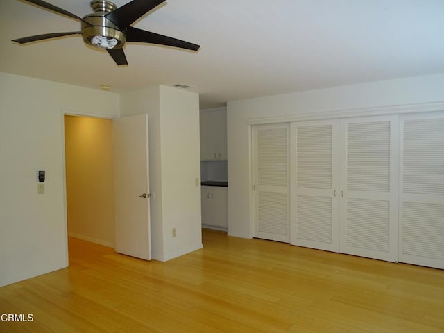 unfurnished bedroom with light hardwood / wood-style flooring, a closet, and ceiling fan