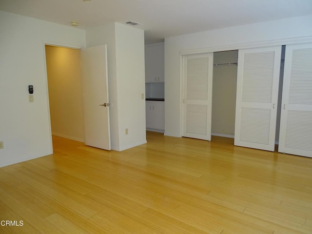 unfurnished bedroom featuring light wood-type flooring and a closet