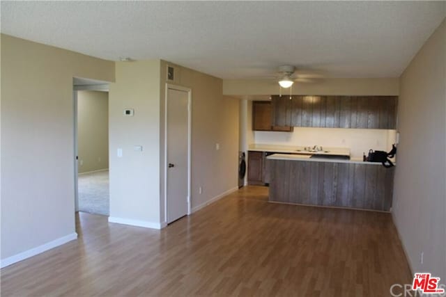 kitchen featuring washer / dryer, hardwood / wood-style flooring, ceiling fan, kitchen peninsula, and a textured ceiling