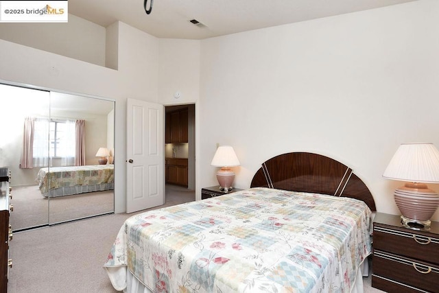 carpeted bedroom featuring a towering ceiling and a closet