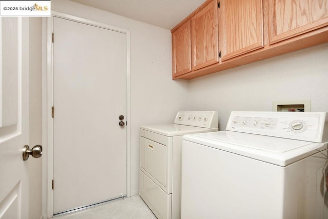 clothes washing area featuring cabinets and separate washer and dryer