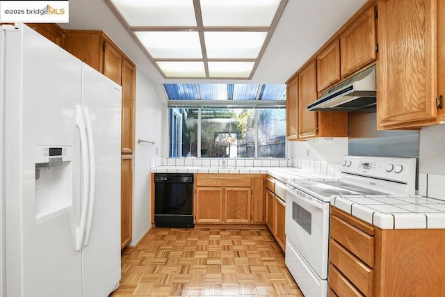 kitchen featuring white appliances, tile counters, and light parquet floors