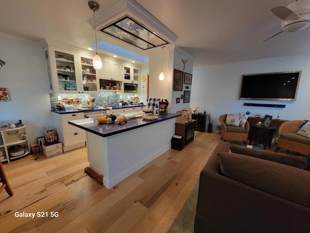 kitchen featuring white cabinetry, crown molding, light hardwood / wood-style flooring, pendant lighting, and ceiling fan