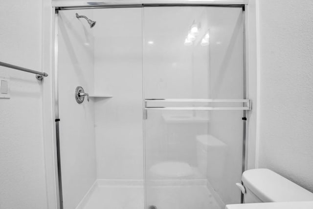 bathroom featuring toilet and a shower with door