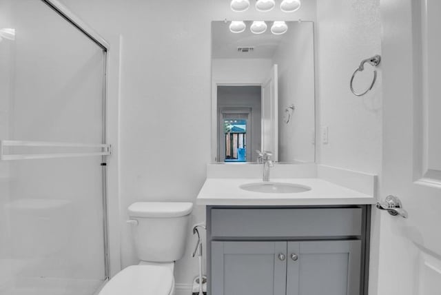 bathroom featuring vanity, walk in shower, and toilet