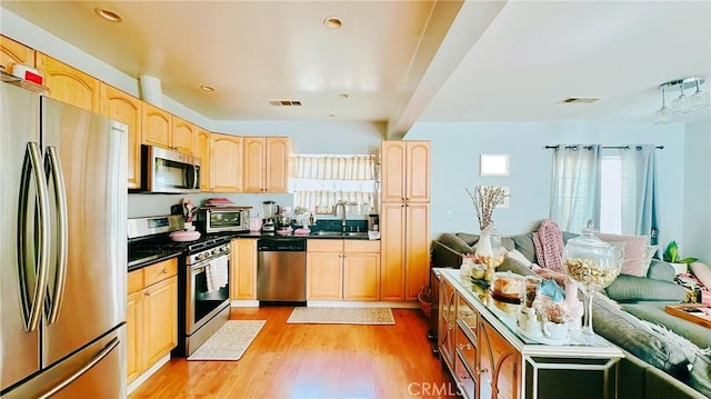 kitchen featuring stainless steel appliances, sink, light brown cabinets, and light wood-type flooring