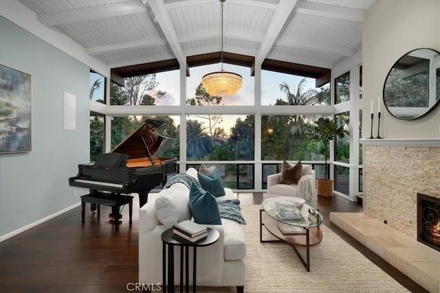 sunroom with lofted ceiling with beams, a tiled fireplace, and plenty of natural light