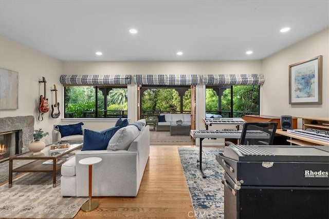 living room with a high end fireplace and light hardwood / wood-style flooring