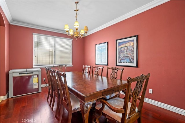 dining area featuring dark hardwood / wood-style flooring, crown molding, and a chandelier