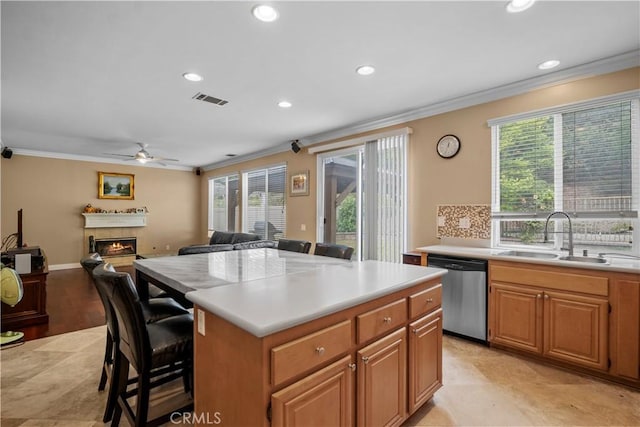 kitchen with a kitchen island, sink, a breakfast bar area, ornamental molding, and stainless steel dishwasher