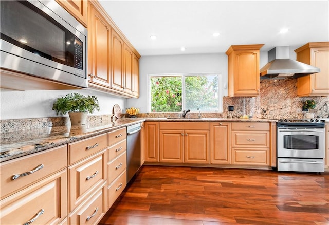 kitchen featuring sink, stainless steel appliances, light stone countertops, light brown cabinetry, and wall chimney exhaust hood