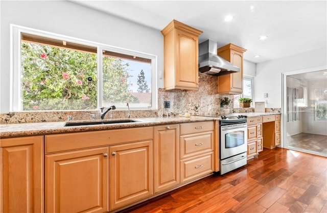 kitchen featuring stainless steel range with electric stovetop, wall chimney range hood, plenty of natural light, and sink