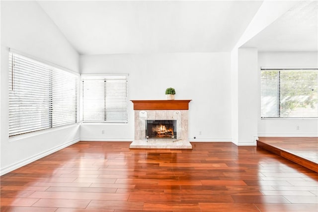 unfurnished living room featuring hardwood / wood-style flooring, vaulted ceiling, and a high end fireplace