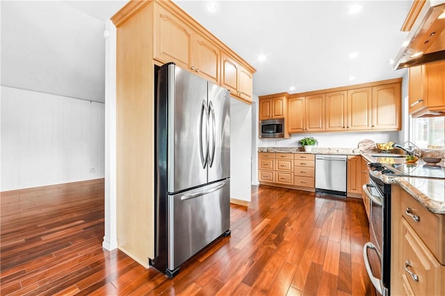 kitchen featuring stainless steel appliances, light stone counters, extractor fan, dark hardwood / wood-style flooring, and light brown cabinets