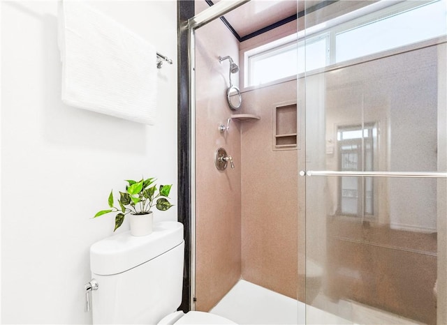 bathroom with a shower with shower door and toilet