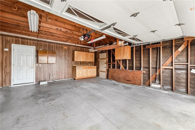 garage with a garage door opener and wooden walls