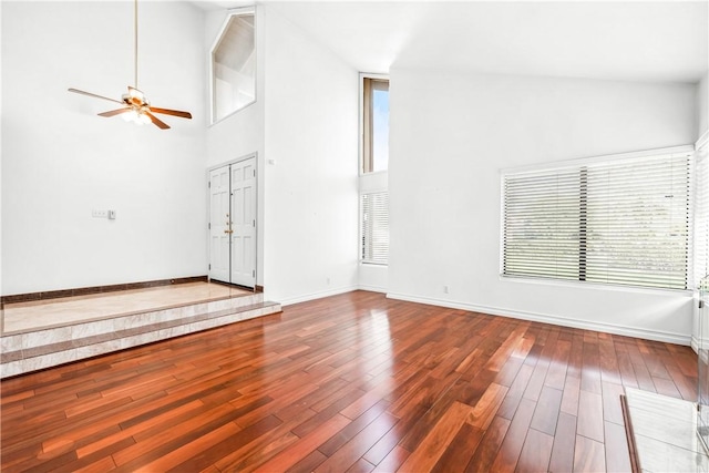 unfurnished living room with a towering ceiling, hardwood / wood-style floors, and ceiling fan