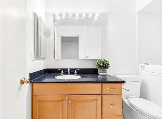 bathroom with vanity, toilet, and washer / dryer