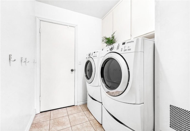 laundry area with separate washer and dryer, light tile patterned floors, and cabinets