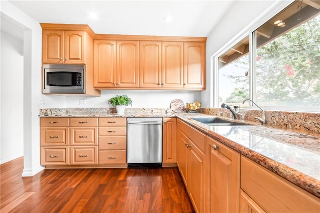 kitchen with light brown cabinetry, sink, light stone counters, appliances with stainless steel finishes, and dark hardwood / wood-style flooring