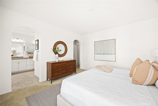 bedroom with sink, light carpet, and ensuite bath