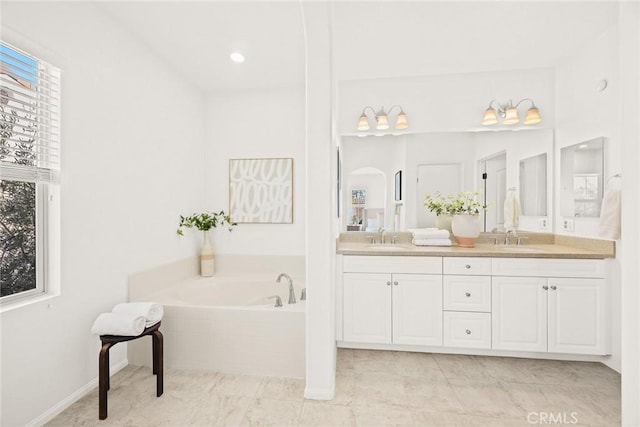 bathroom with a relaxing tiled tub, vanity, and tile patterned flooring