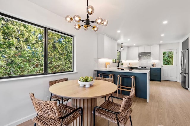 dining area with sink, a wealth of natural light, a chandelier, and light wood-type flooring