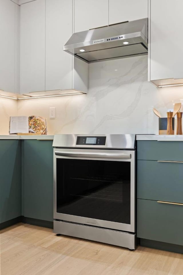 kitchen with tasteful backsplash, stainless steel electric range, and light wood-type flooring