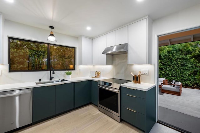 kitchen with sink, white cabinetry, decorative light fixtures, appliances with stainless steel finishes, and light hardwood / wood-style floors