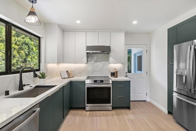 kitchen with sink, white cabinetry, stainless steel appliances, decorative backsplash, and decorative light fixtures