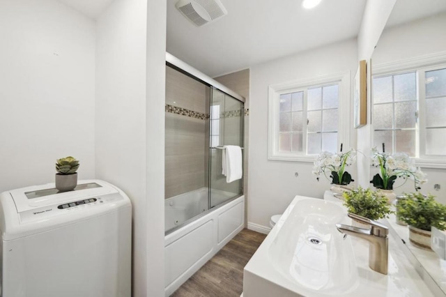 bathroom featuring wood-type flooring, combined bath / shower with glass door, and toilet