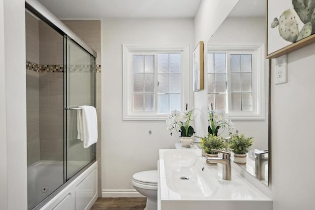 full bathroom with wood-type flooring, toilet, combined bath / shower with glass door, and vanity