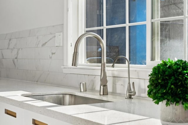 details featuring light stone counters, sink, and tasteful backsplash