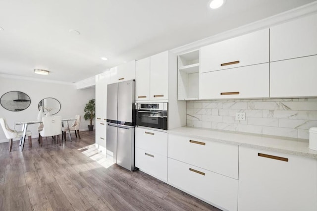 kitchen with appliances with stainless steel finishes, tasteful backsplash, white cabinets, crown molding, and light wood-type flooring