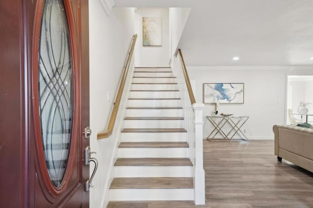 staircase with hardwood / wood-style floors and ornamental molding