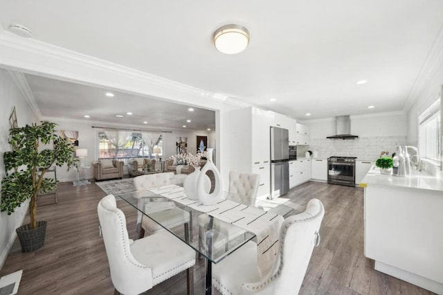 dining space with sink, wood-type flooring, and ornamental molding