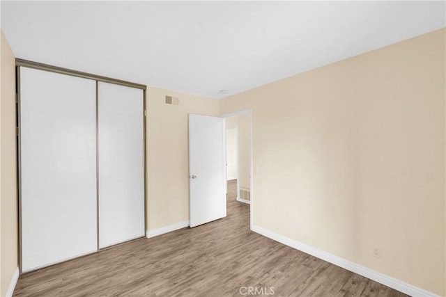 unfurnished bedroom featuring light hardwood / wood-style floors and a closet